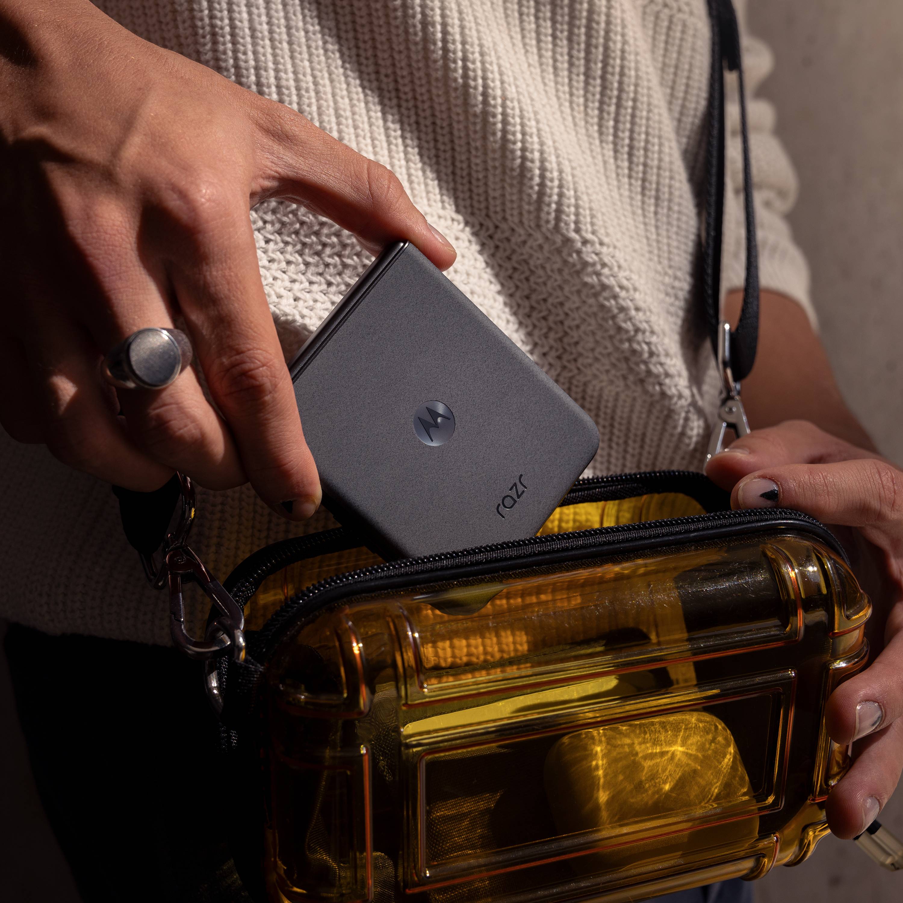 Person hält ein kleines, quadratisches Gerät mit dem Text 'RALT', über einer durchsichtigen gelben Tasche.