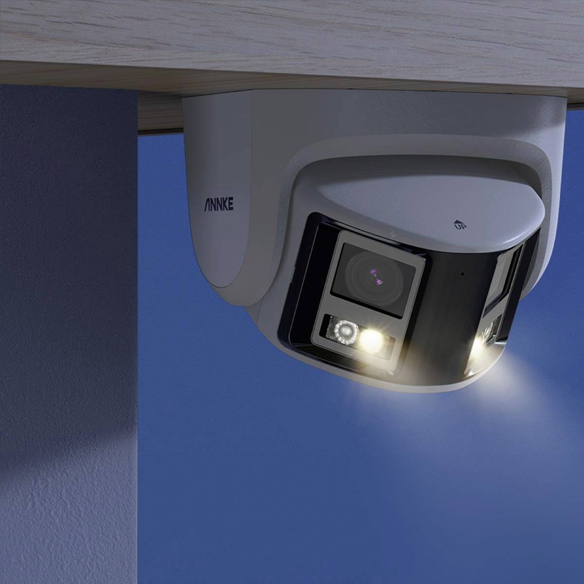 Überwachungskamera an einer Decke montiert, leuchtet mit LED-Lichtern. Sie ist teilweise im dunklen Raum sichtbar.