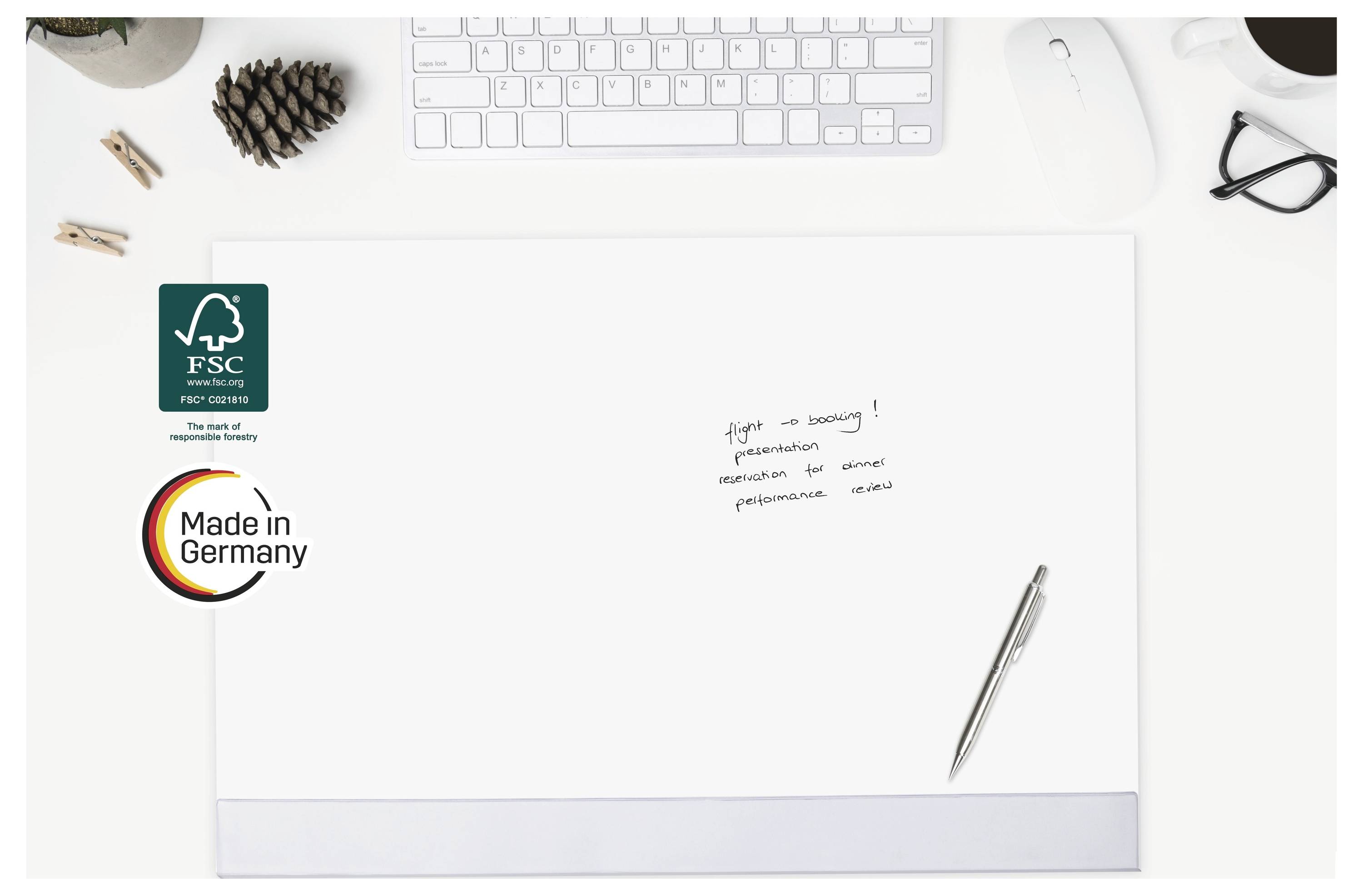 Draufsicht auf ein leeres weißes Blatt Papier auf einem Schreibtisch mit einem silbernen Stift, einer Tastatur, einer Maus und FSC- sowie „Made in Germany"-Logos auf der linken Seite.