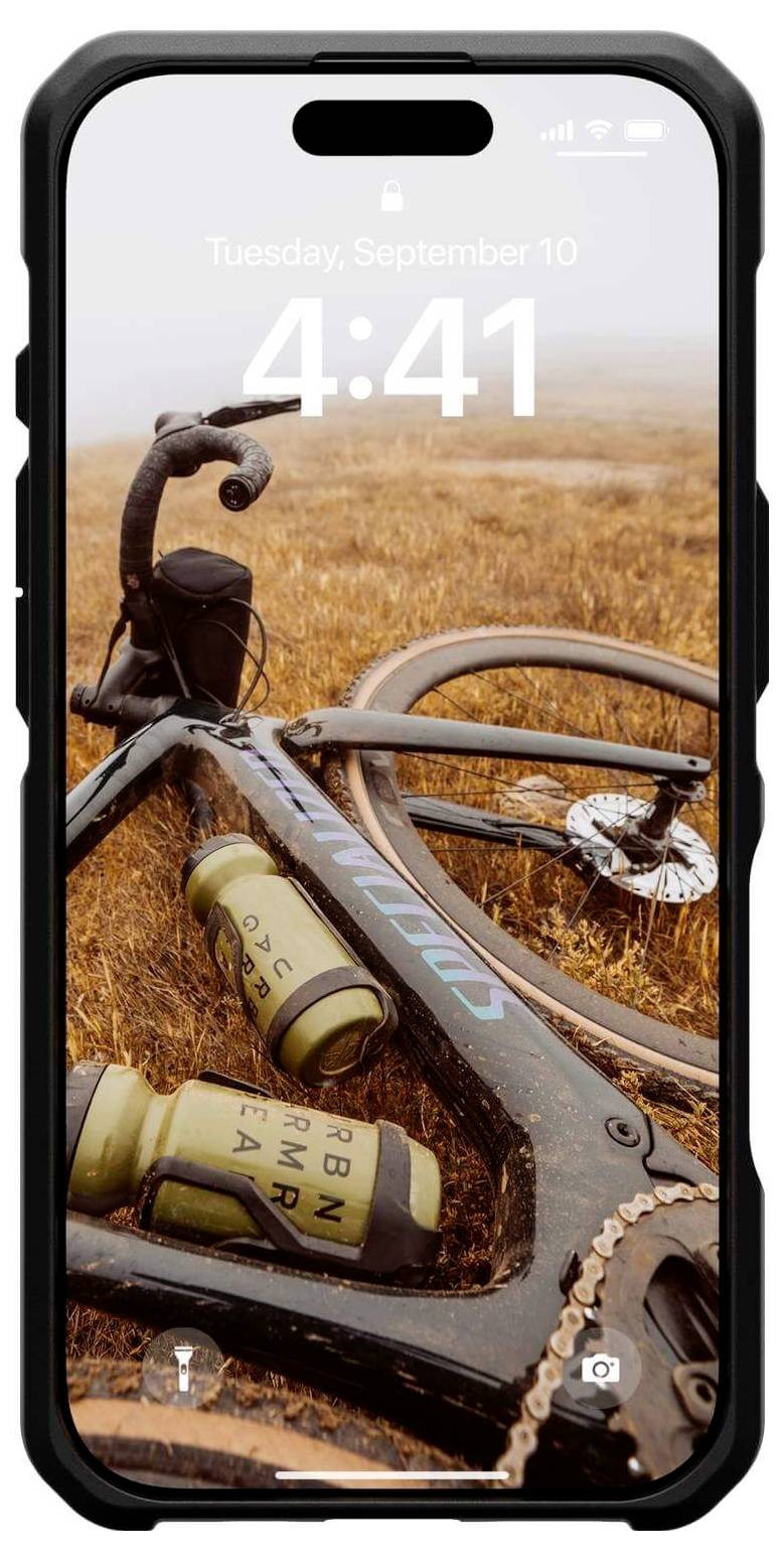 Ein Fahrrad mit orangefarbenen Trinkflaschen liegt auf einem Feld. Der Handybildschirm zeigt Dienstag, 10. September, 4:41 Uhr an.