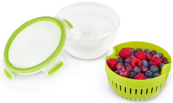 Ein geschlossener Behälter mit Deckel neben einem Sieb mit frischen Himbeeren und Blaubeeren. Ideal zum Waschen und Aufbewahren.