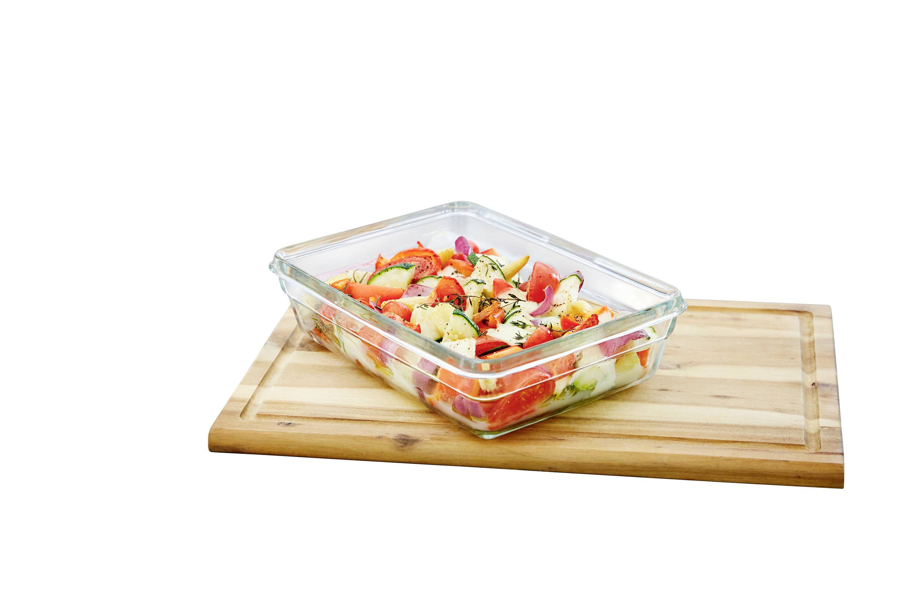 Ein Glasbehälter mit buntem Gemüsesalat, der Tomaten, Gurken und Paprika enthält, steht auf einem Holzbrett.