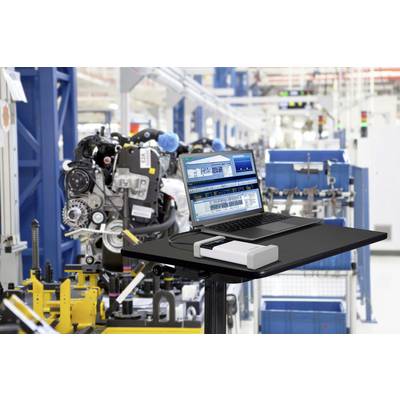 Ein Laptop steht auf einem Tisch in einer Fabrik. Der Bildschirm zeigt Fertigungssoftware. Im Hintergrund sind Maschinen und Produktionslinien zu sehen.
