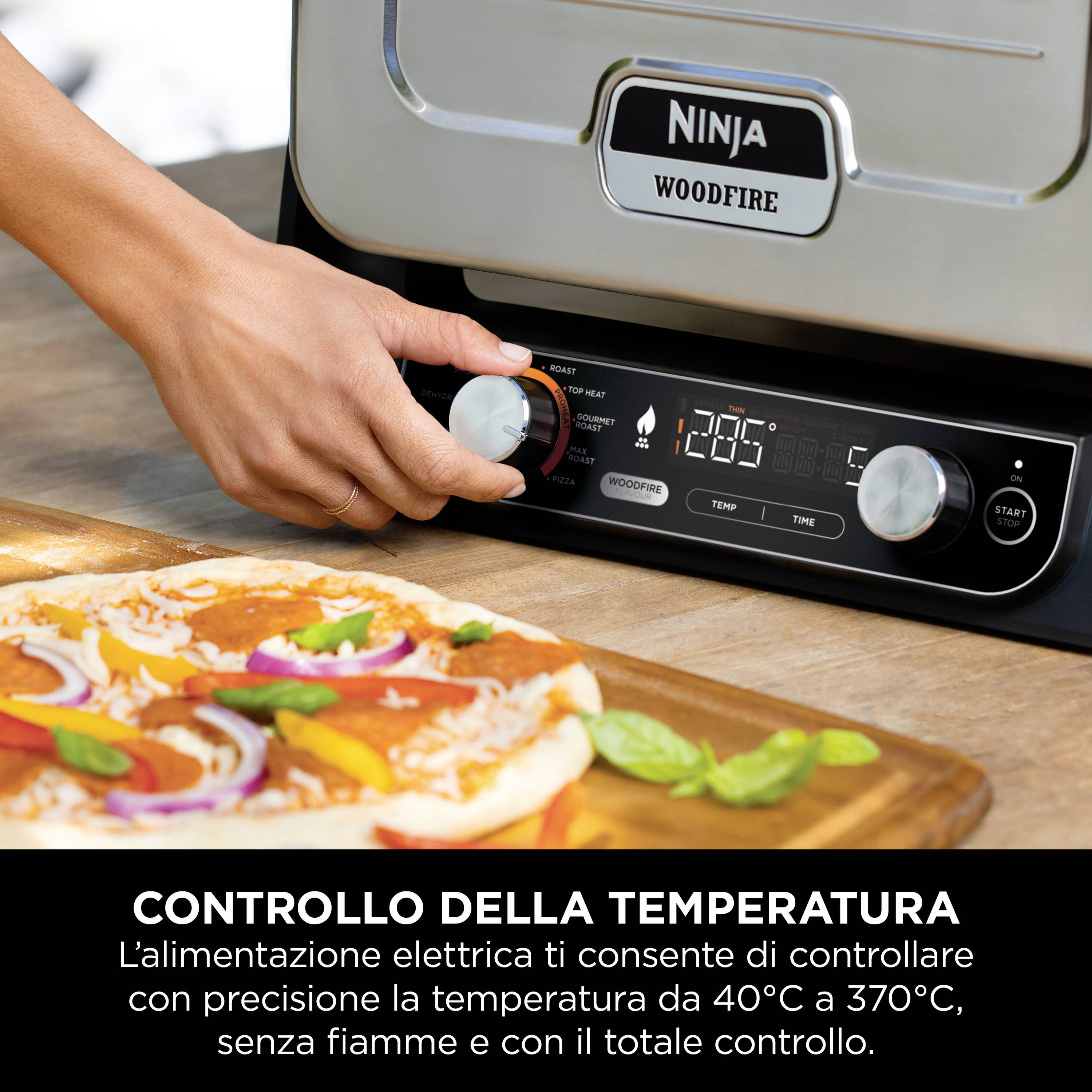 Eine Hand stellt die Temperatur an einem elektrischen Backofen ein. Im Vordergrund liegt eine rohe Pizza mit Basilikumblättern.