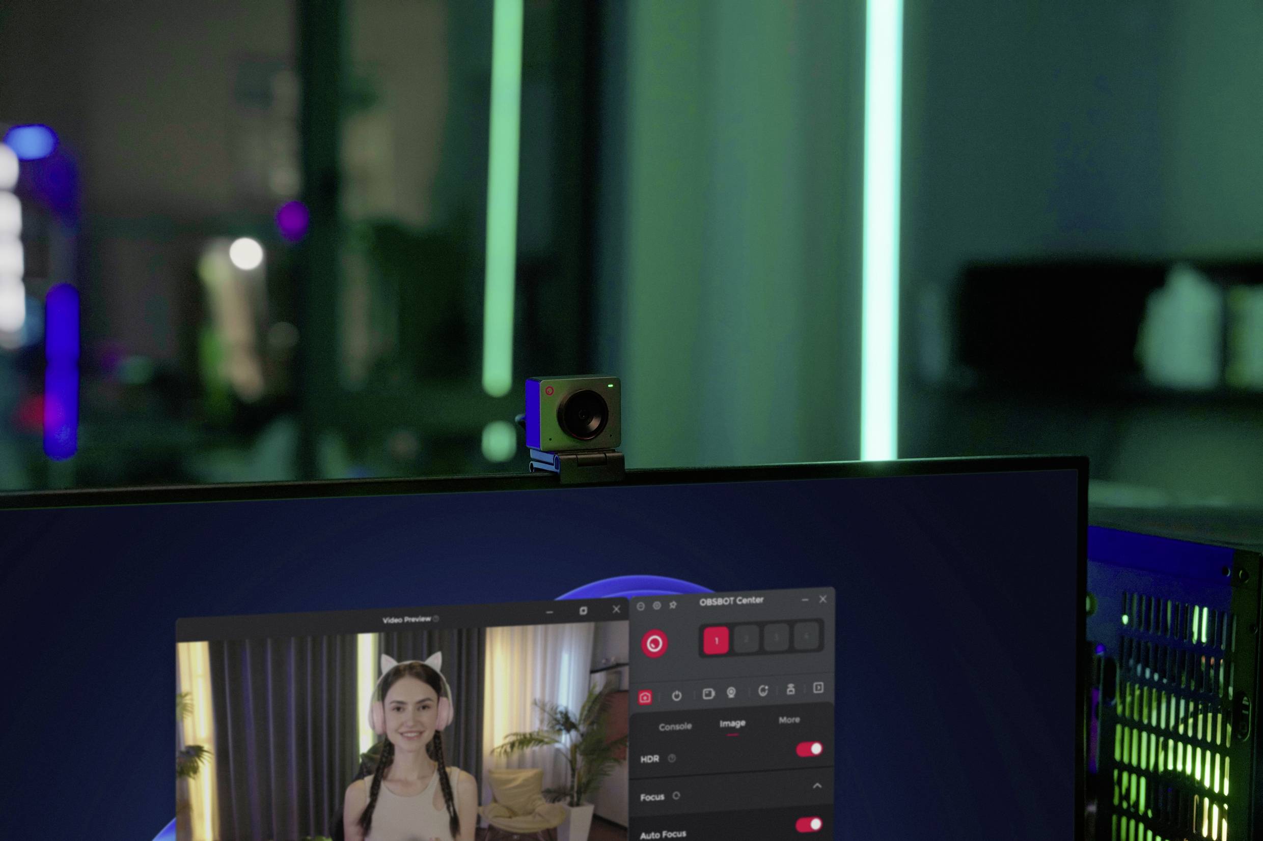 Eine Webcam ist auf einem Monitor montiert, der Videobearbeitungssoftware zeigt. Im Bildschirm ist eine Person zu sehen, die aufgenommen wird.