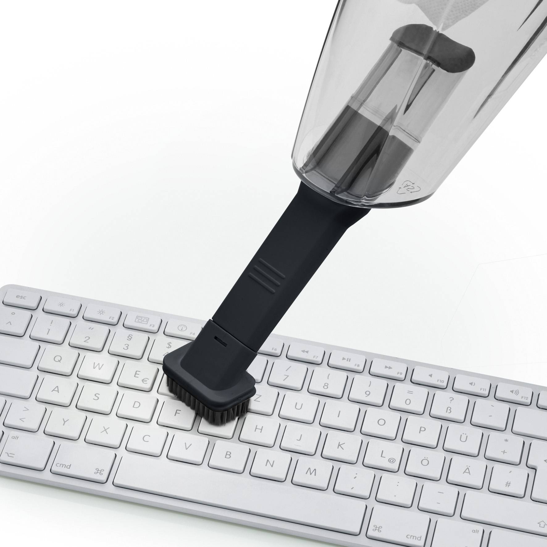 Ein Handstaubsauger mit einer Bürste entfernt Staub von einer Computertastatur.