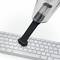 Ein Handstaubsauger mit einer Bürste entfernt Staub von einer Computertastatur.
