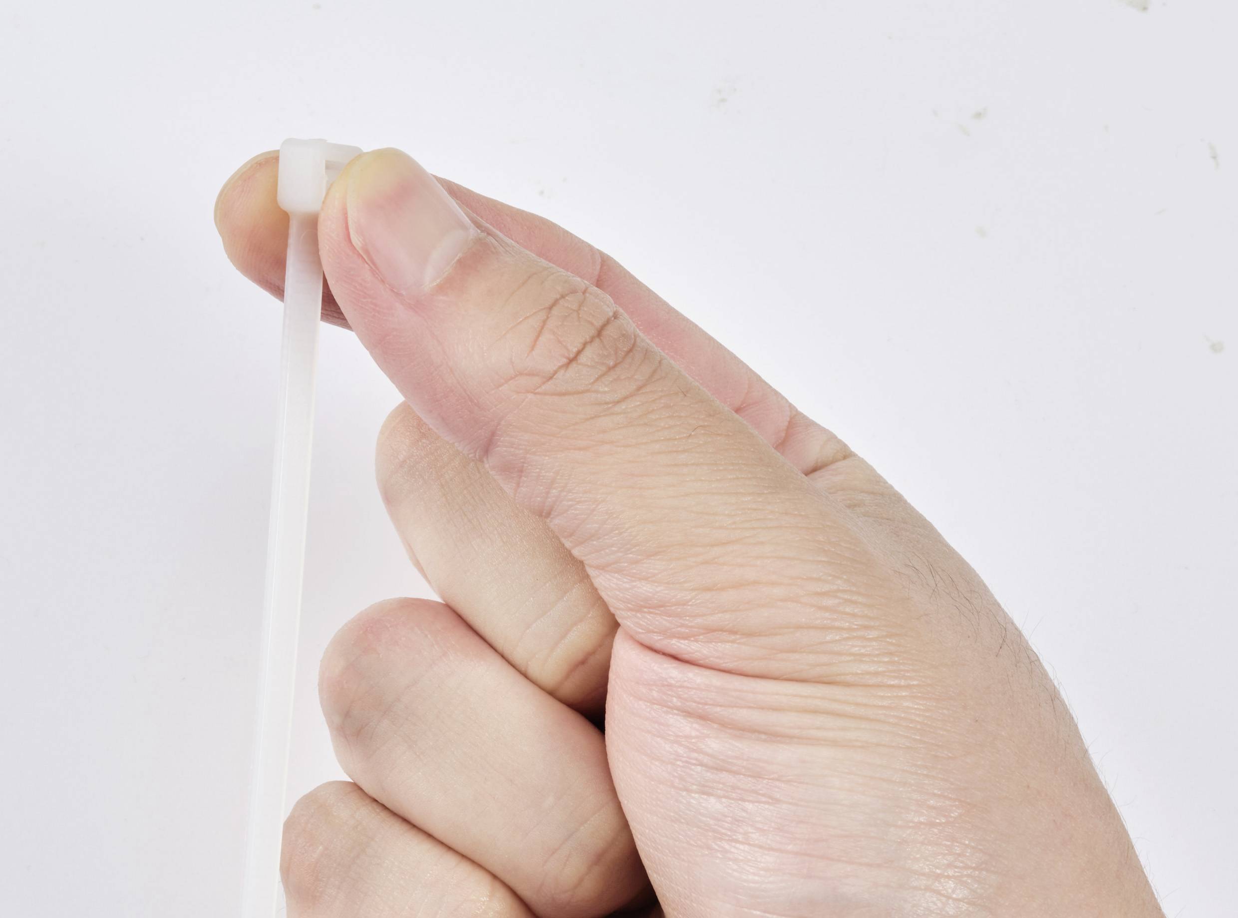 Eine Hand hält einen weißen Kabelbinder bereit zum Befestigen.