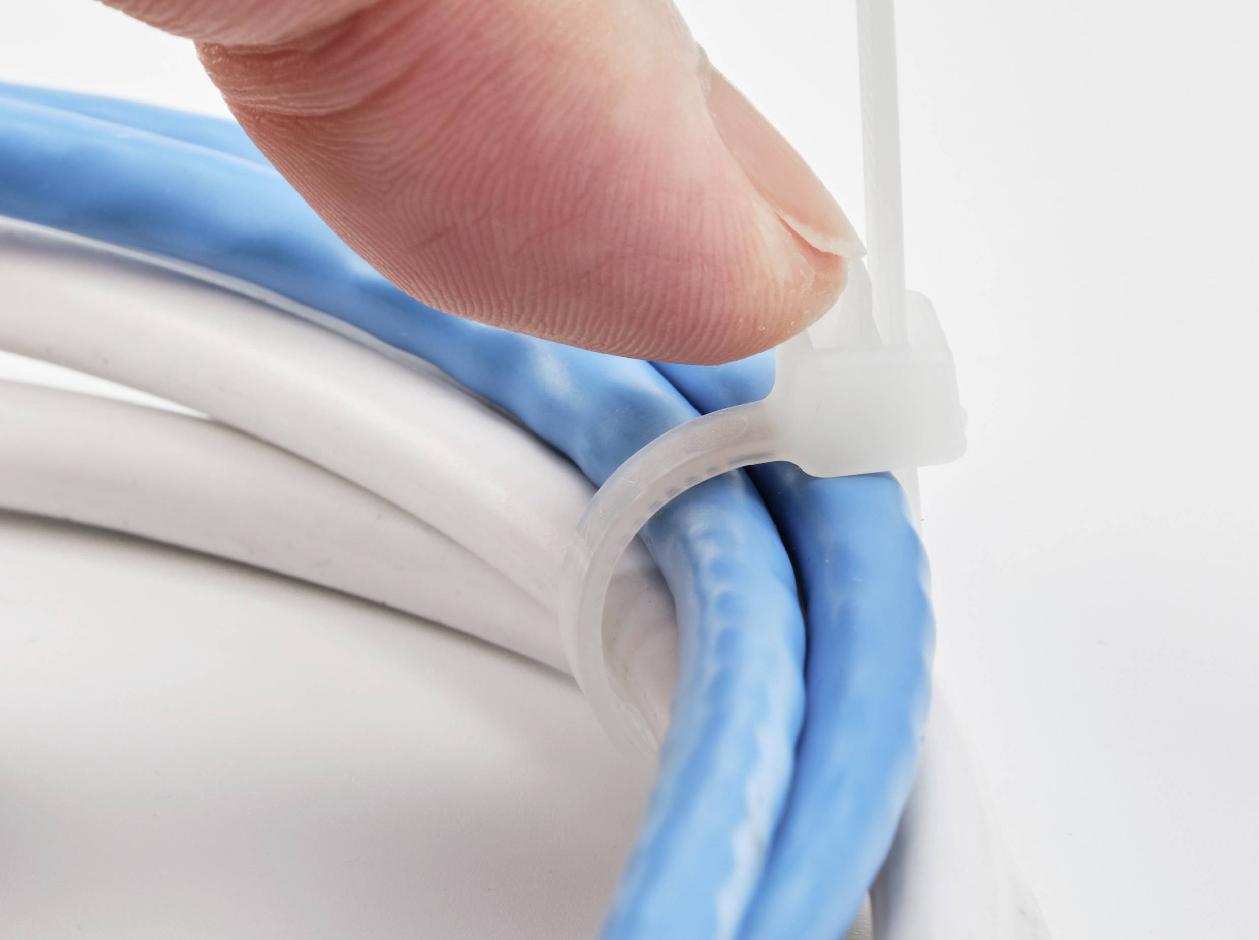 Eine Hand zieht einen Kabelbinder fest, der blaue und weiße Kabel bündelt.