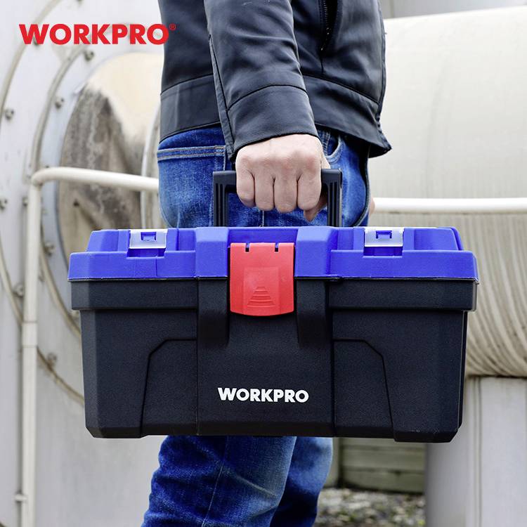 Person hält einen schwarz-blauen Werkzeugkasten von 'WORKPRO' in der Hand. Hintergrund zeigt industrielle Rohre.