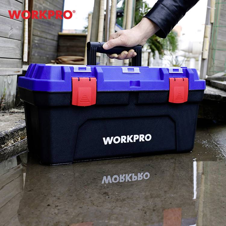 Eine blaue und schwarze Werkzeugkiste mit rotem Verschluss und der Aufschrift 'WORKPRO' wird von einer Hand auf einem Holzdeck getragen.