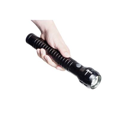 Eine rechte Hand hält eine schwarze, längliche Taschenlampe, die eingeschaltet ist und nach unten leuchtet.