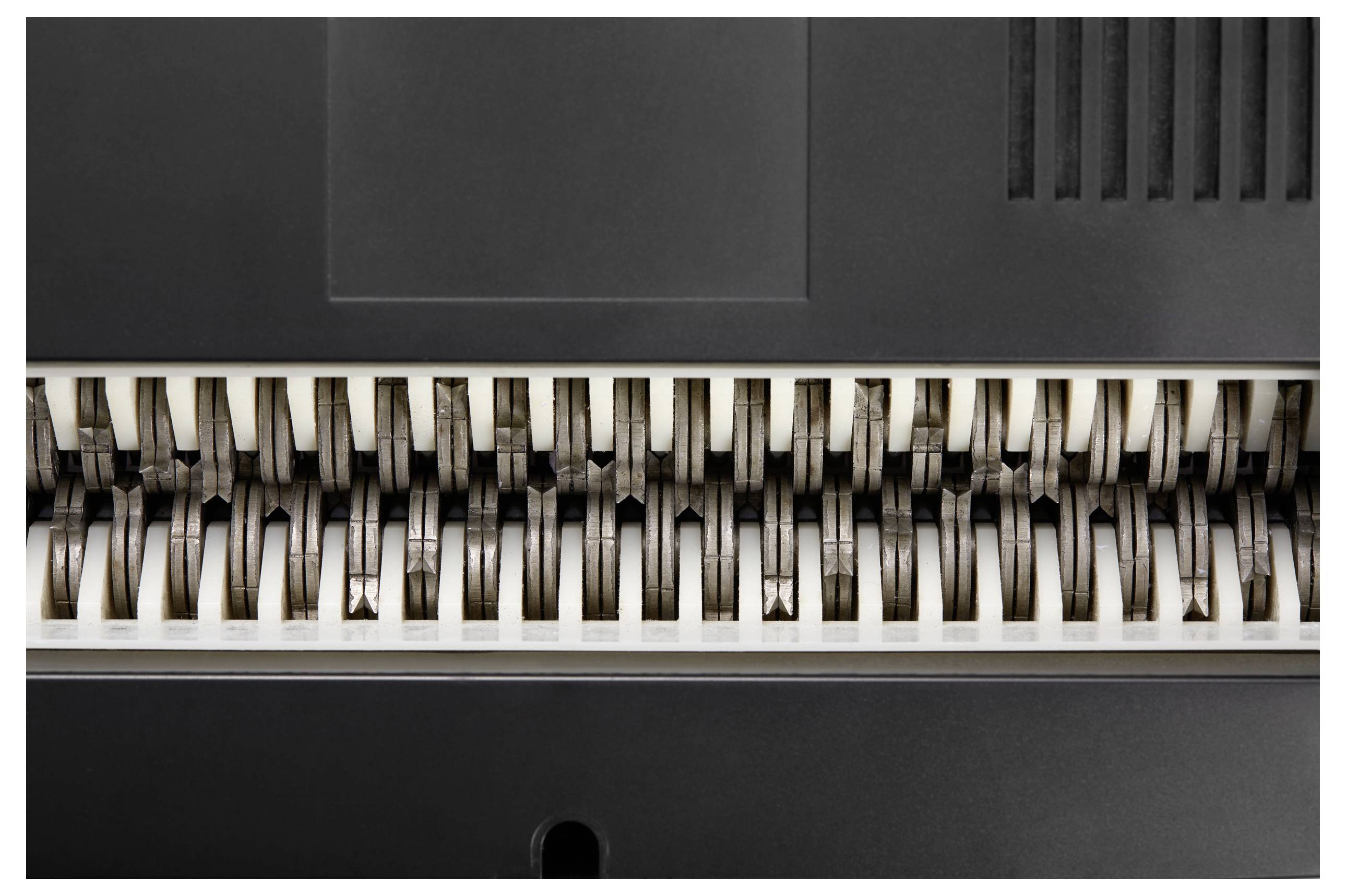 'Nahaufnahme eines Papierschredders mit rotierenden Klingen, die zum Zerkleinern von Papierdokumenten verwendet werden.'