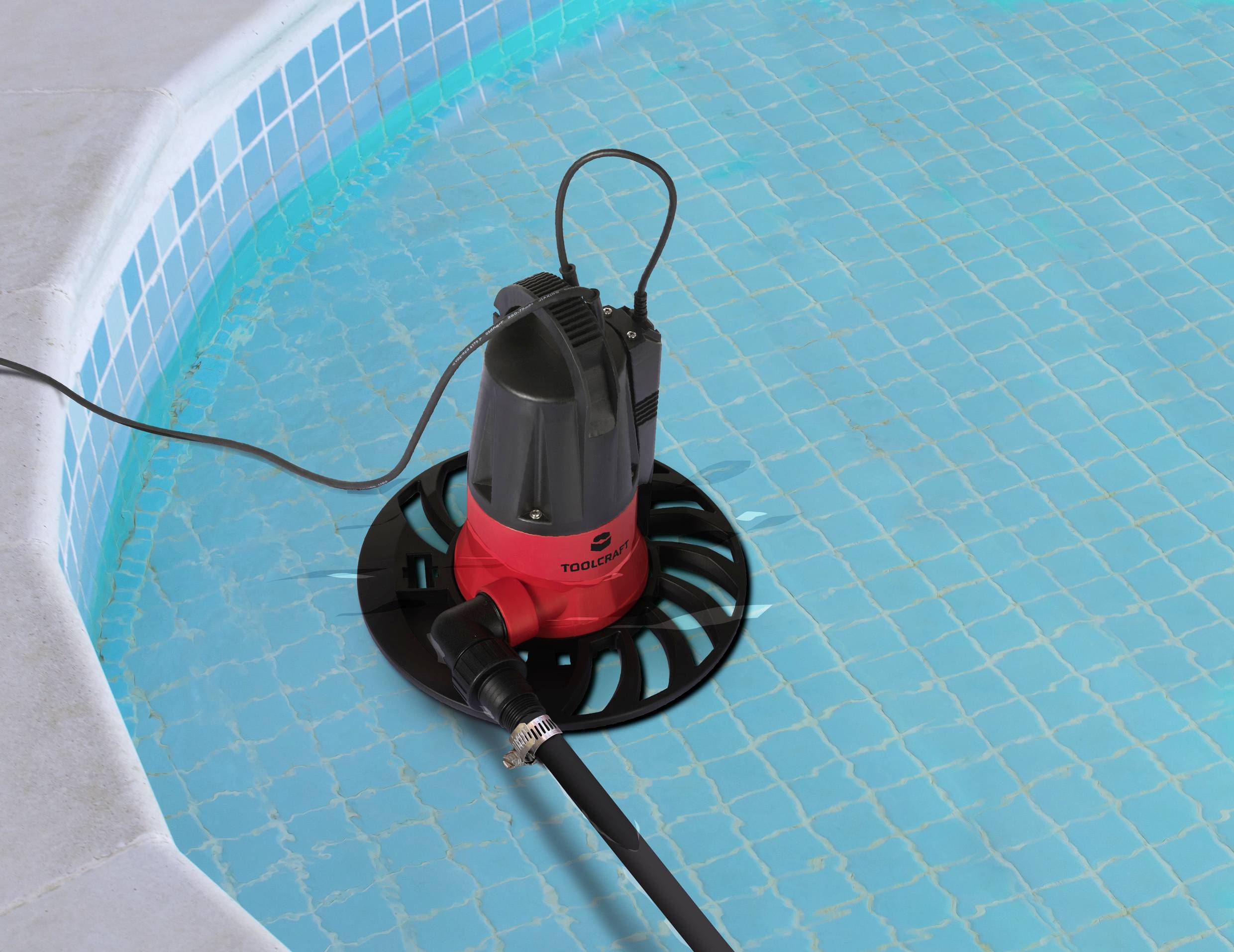 'Eine Pumpe mit Schlauch liegt auf dem Boden eines leeren Pools, bereit zum Abpumpen von Wasser.'