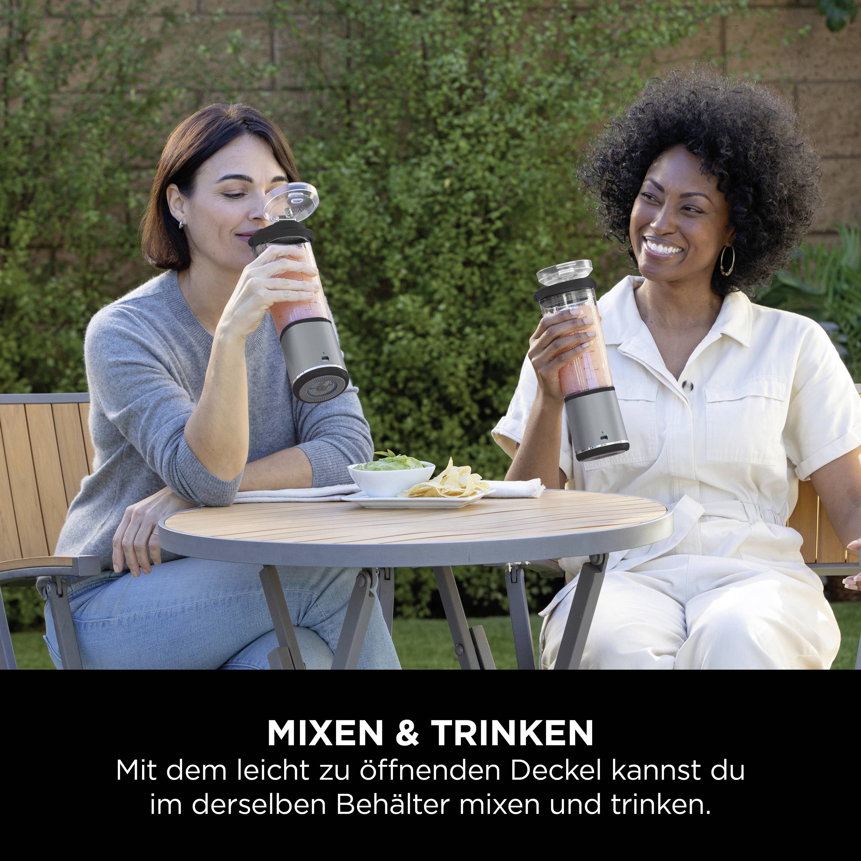 Zwei Frauen sitzen im Freien an einem Tisch, halten Flaschen. Text darunter: 'Mixen & Trinken. Mit dem leicht zu öffnenden Deckel kannst du im selben Behälter mixen und trinken.'