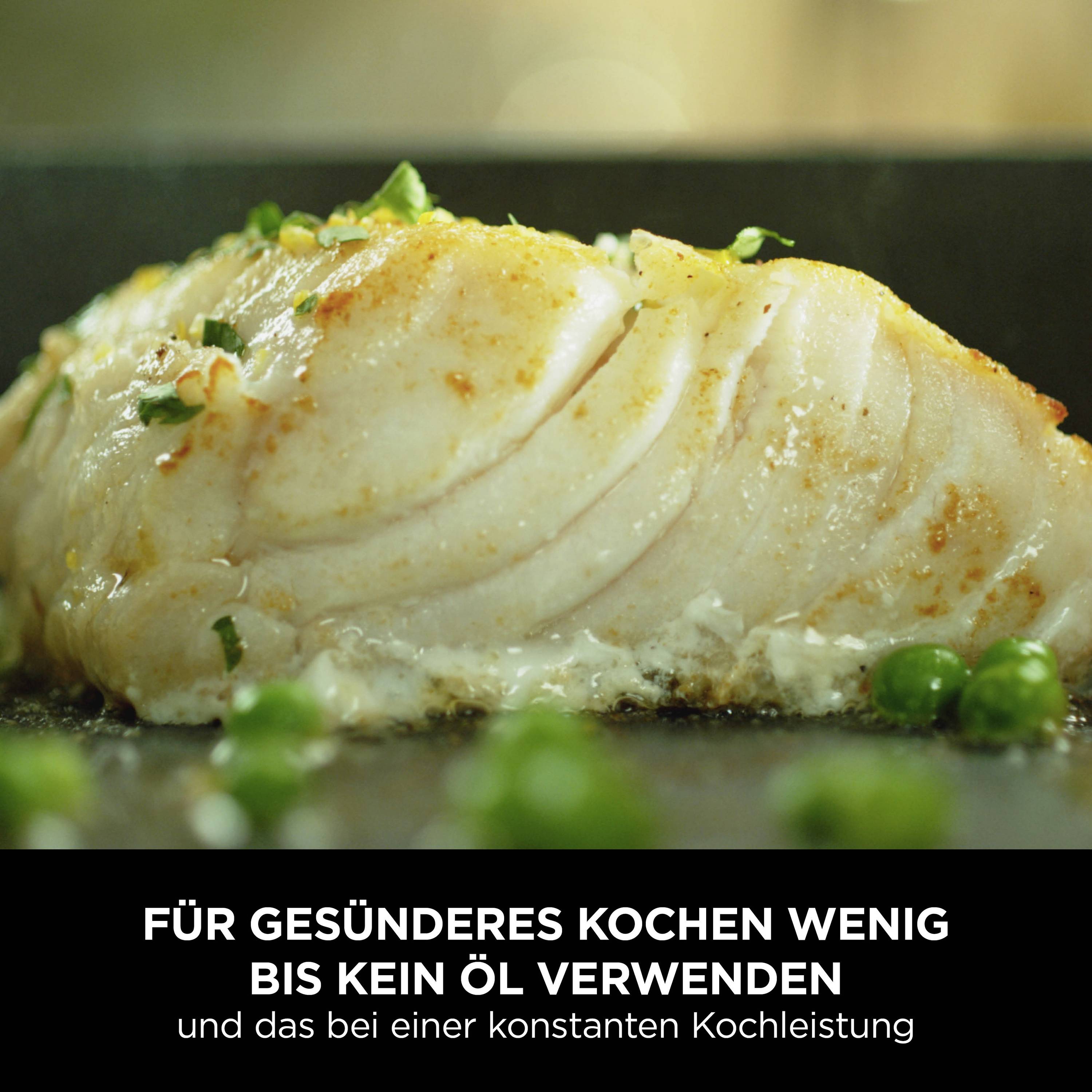 Nahaufnahme eines gebratenen Fischfilets mit knuspriger Kruste. Im Hintergrund sind Erbsen zu sehen. Text im Bild: 'Für gesünderes Kochen wenig bis kein Öl verwenden und das bei einer konstanten Kochleistung'.