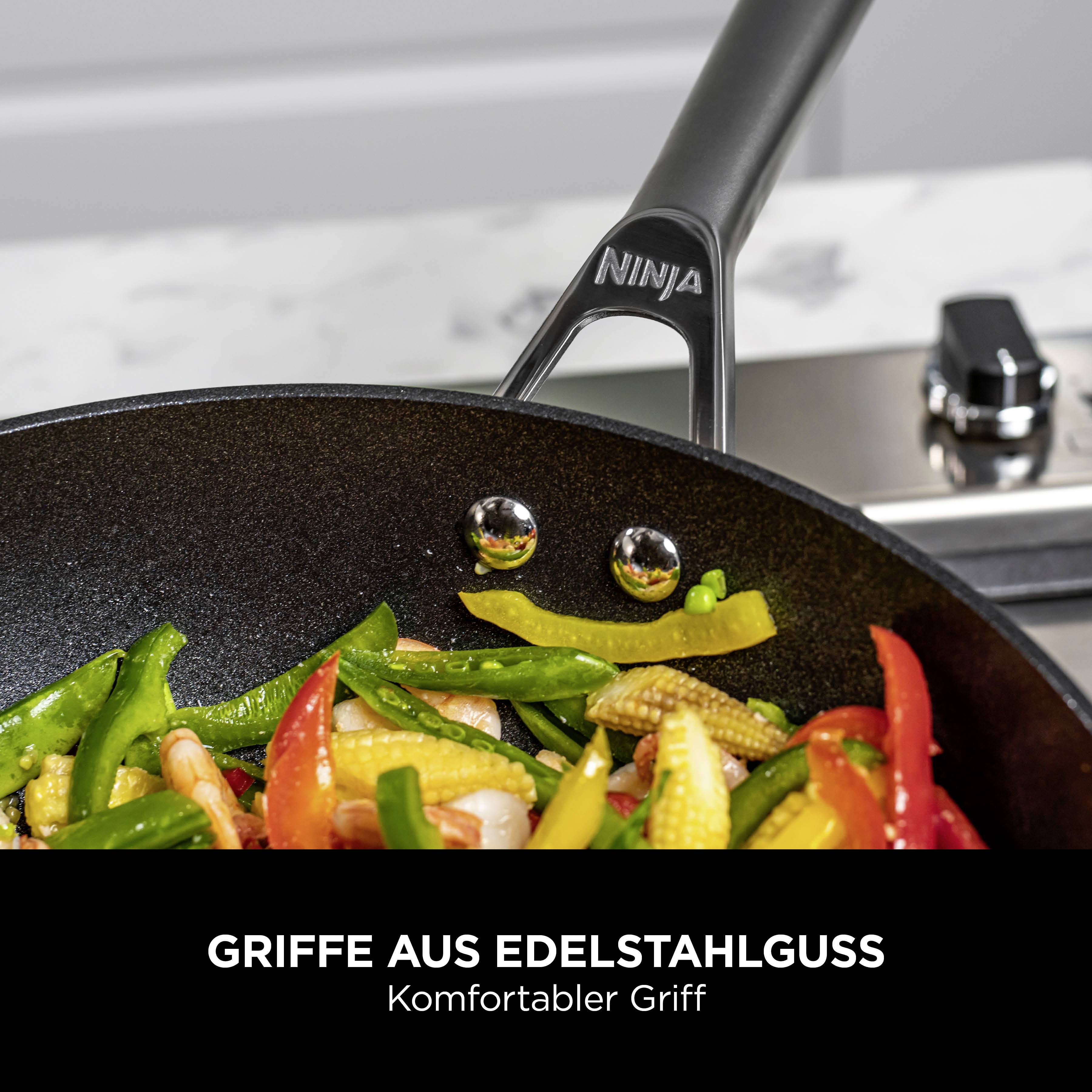 Eine Pfanne mit buntem Gemüse auf einem Herd. Der Griff trägt den Schriftzug 'Ninja'. Text beschreibt den Edelstahlgriff.
