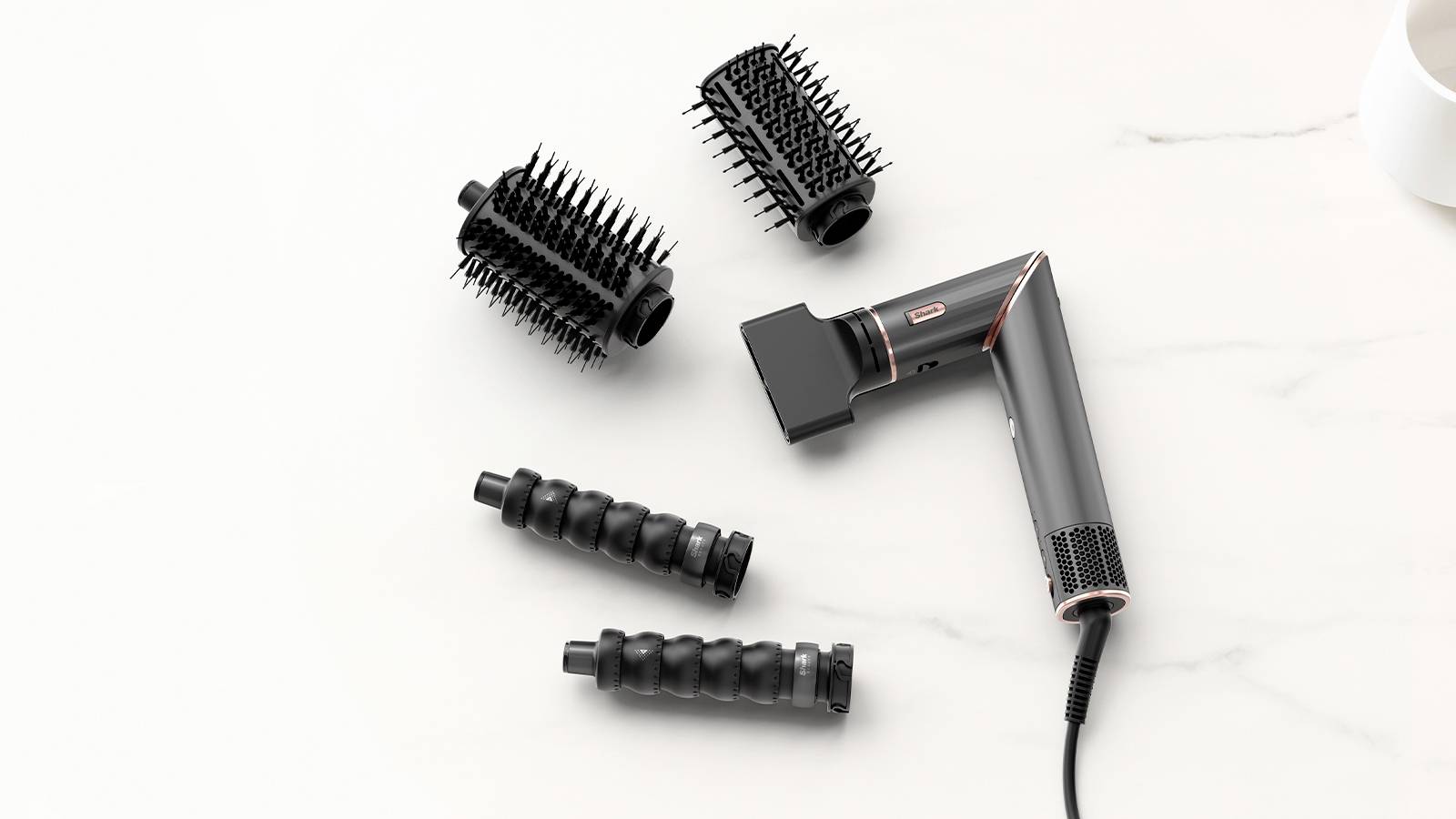 Haartrockner mit vier verschiedenen Aufsätzen auf einer weißen Marmoroberfläche, die verschiedene Styling-Optionen bieten.