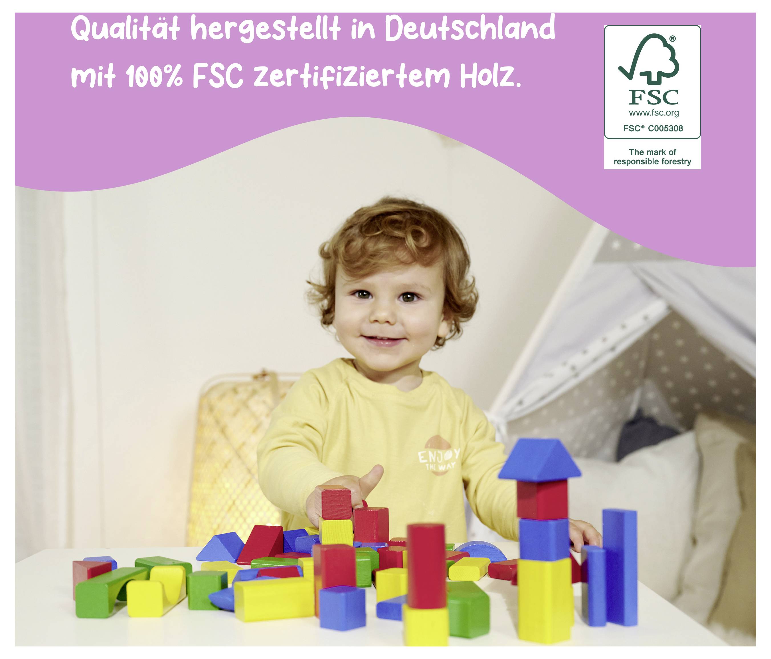 Kleines Kind sitzt an einem Tisch und spielt mit bunten Holzbauklötzen. Text oben: 'Qualität hergestellt in Deutschland mit 100% FSC zertifiziertem Holz.'