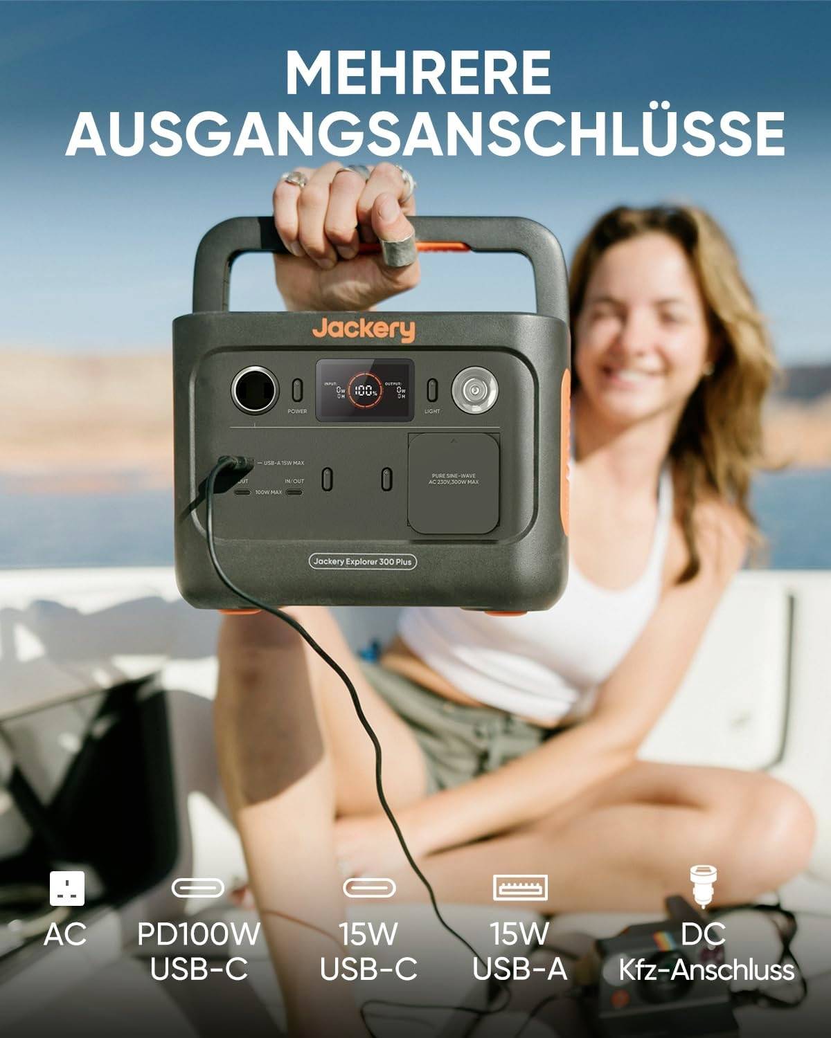 Eine Frau hält eine tragbare Powerstation mit mehreren Anschlüssen. Im Hintergrund ist ein See zu sehen, mit dem Text 'Mehrere Ausgangsanschlüsse' oben.