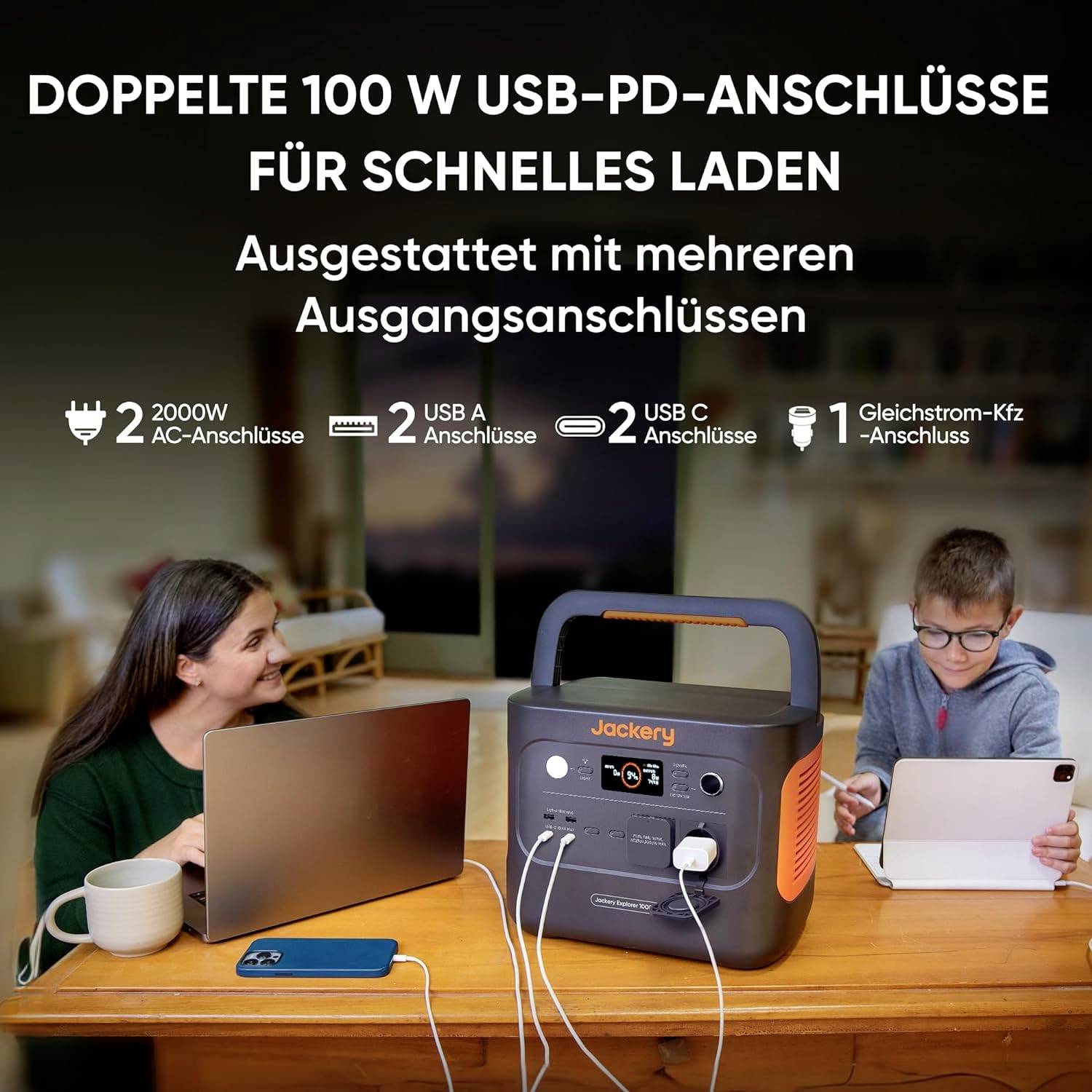 Eine Frau und ein Mann sitzen am Tisch und nutzen Geräte, die in eine Jackery Powerstation eingesteckt sind. Oben Text über Anschlüsse.