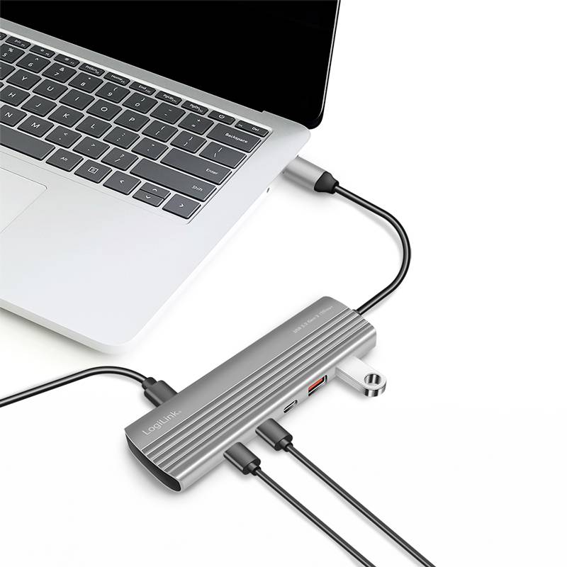 Ein Laptop ist über diverse Kabel mit einem USB-C-Hub verbunden, der zusätzliche Anschlüsse wie USB und HDMI bereitstellt.