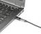 Ein Ladekabel ist in den seitlichen Anschluss eines schwarzen Laptops eingesteckt. Der Laptop zeigt eine QWERTY-Tastatur.