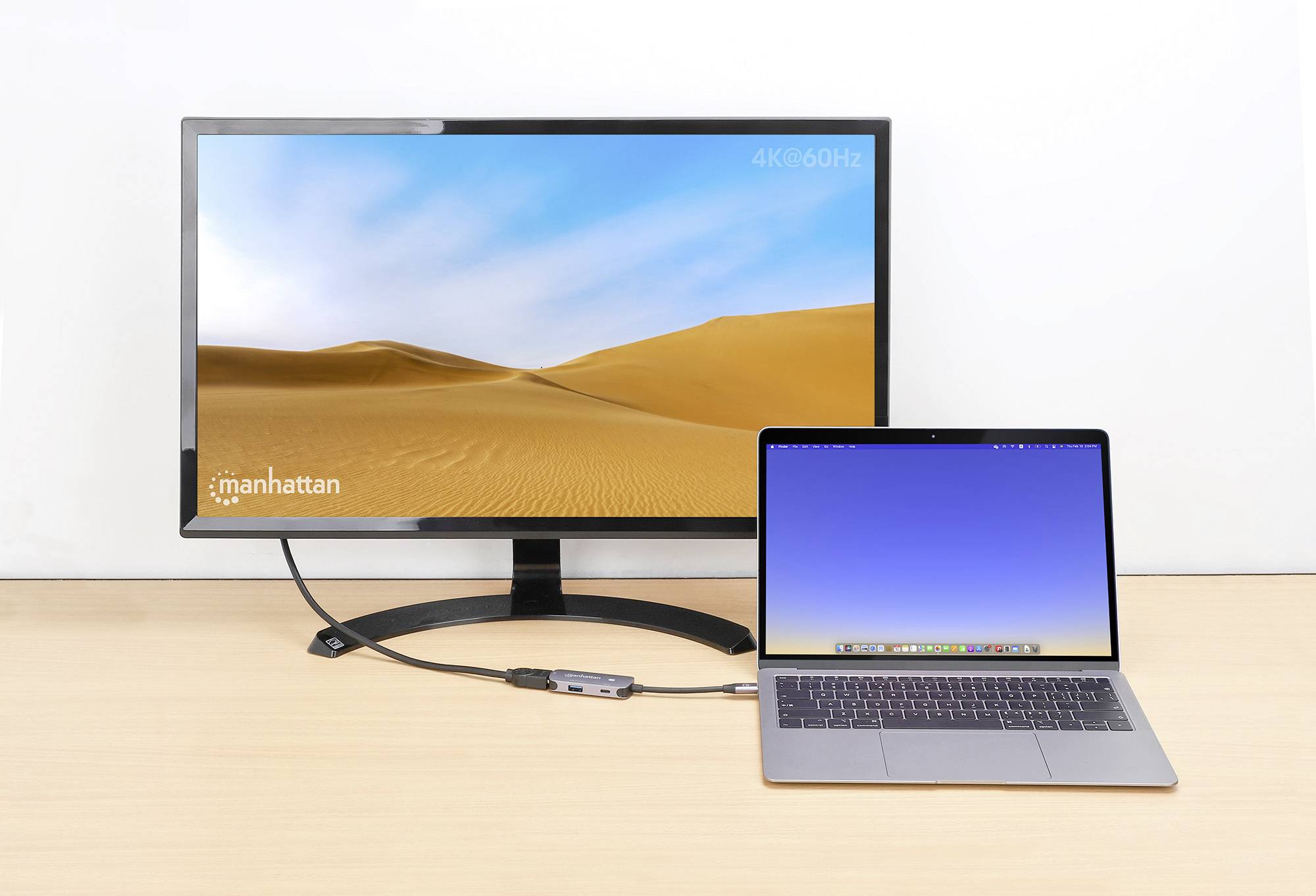 Ein Laptop ist über ein Kabel mit einem größeren Monitor verbunden. Der Monitor zeigt eine Wüstenlandschaft bei 4K-Auflösung an.