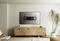 Ein modernes Wohnzimmer mit einem Holzsideboard und einem Wandfernseherhalter an der Wand. Eine Pflanze steht neben dem Sideboard.