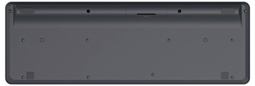 Unterseite einer Tastatur mit Batteriefach in der Mitte und kleinen Schrauben an den Ecken, gezeigt von der Rückseite.