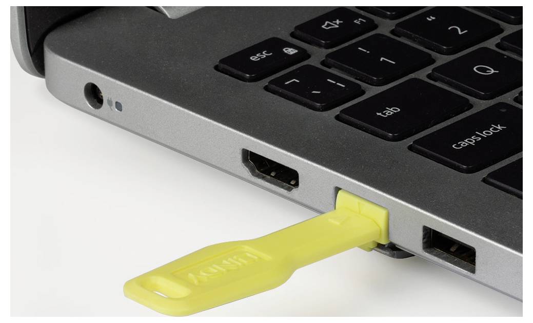 Ein gelber USB-Stick ist in den Seitenport eines Laptops eingesteckt und zeigt die Verbindung eines Datenspeichers.