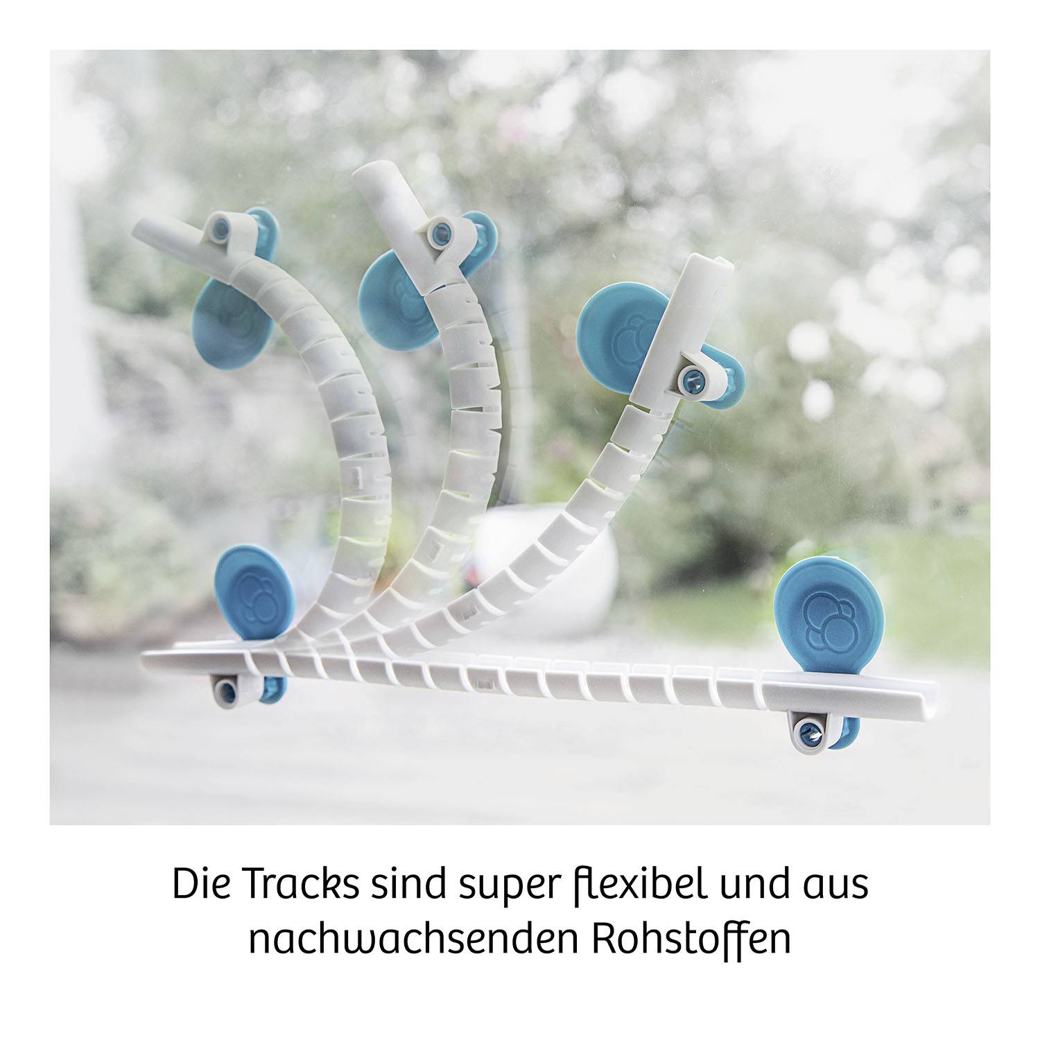 Die Bild zeigt flexible weiße Tracks mit blauen Rädern, dargestellt in verschiedenen Positionen. Unterschrift: 'Die Tracks sind super flexibel und aus nachwachsenden Rohstoffen'.