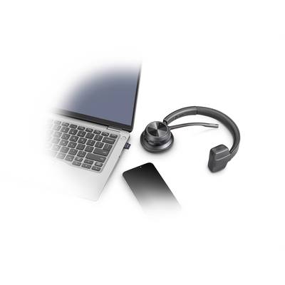 Ein Laptop mit Tastatur, ein Headset auf einer Ladestation und ein Smartphone nebeneinander auf einem Tisch.
