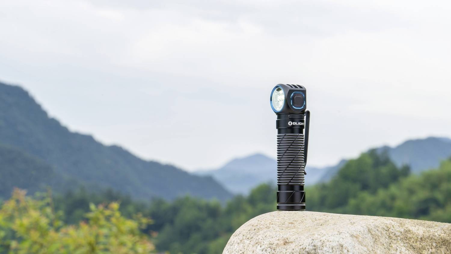 Eine Taschenlampe steht auf einem Felsen mit einer Gebirgslandschaft im Hintergrund.