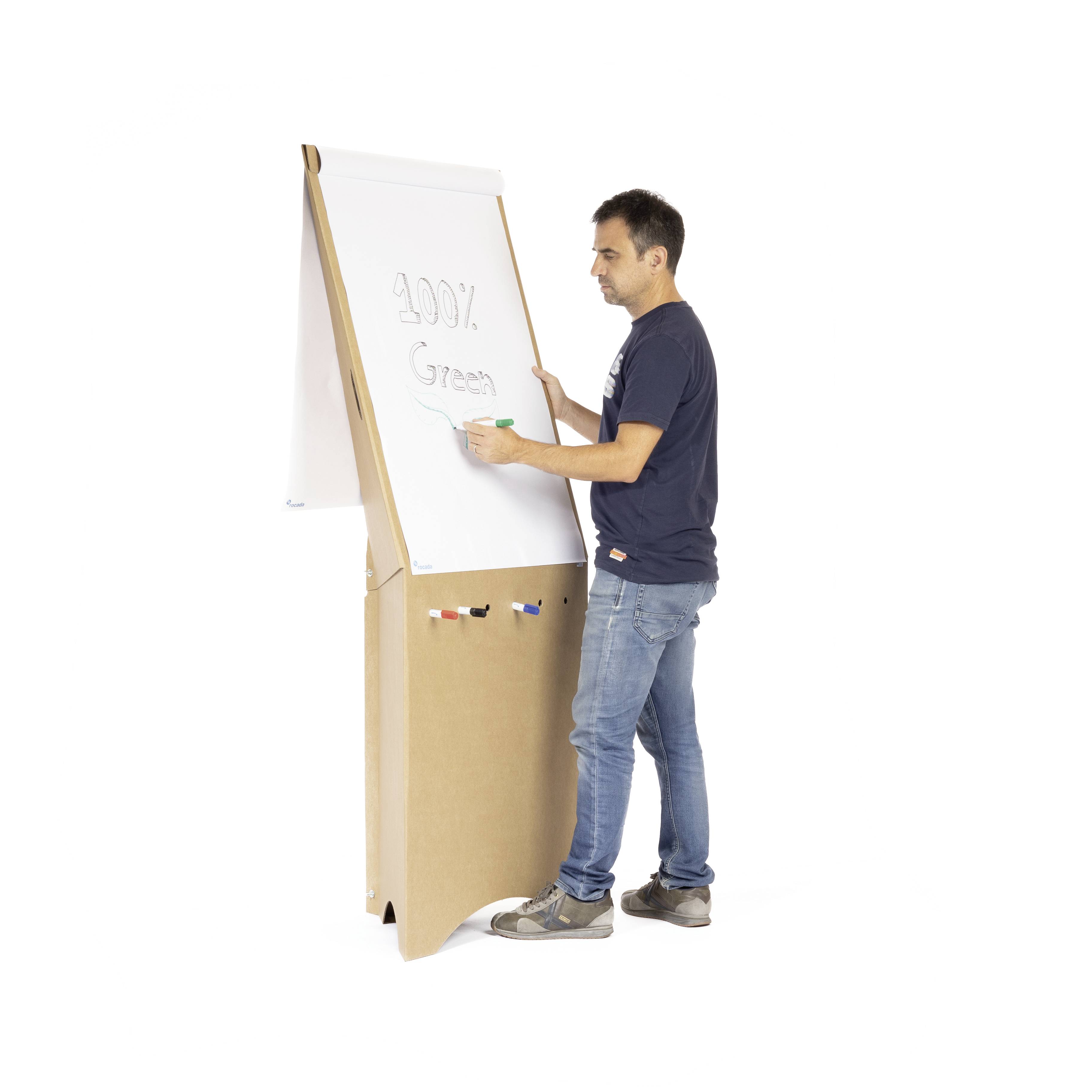 Mann schreibt '100% Green' auf ein Flipchart mit grünem Stift. Flipchart hat Rollen und Stifthalter, steht auf hellem Boden.
