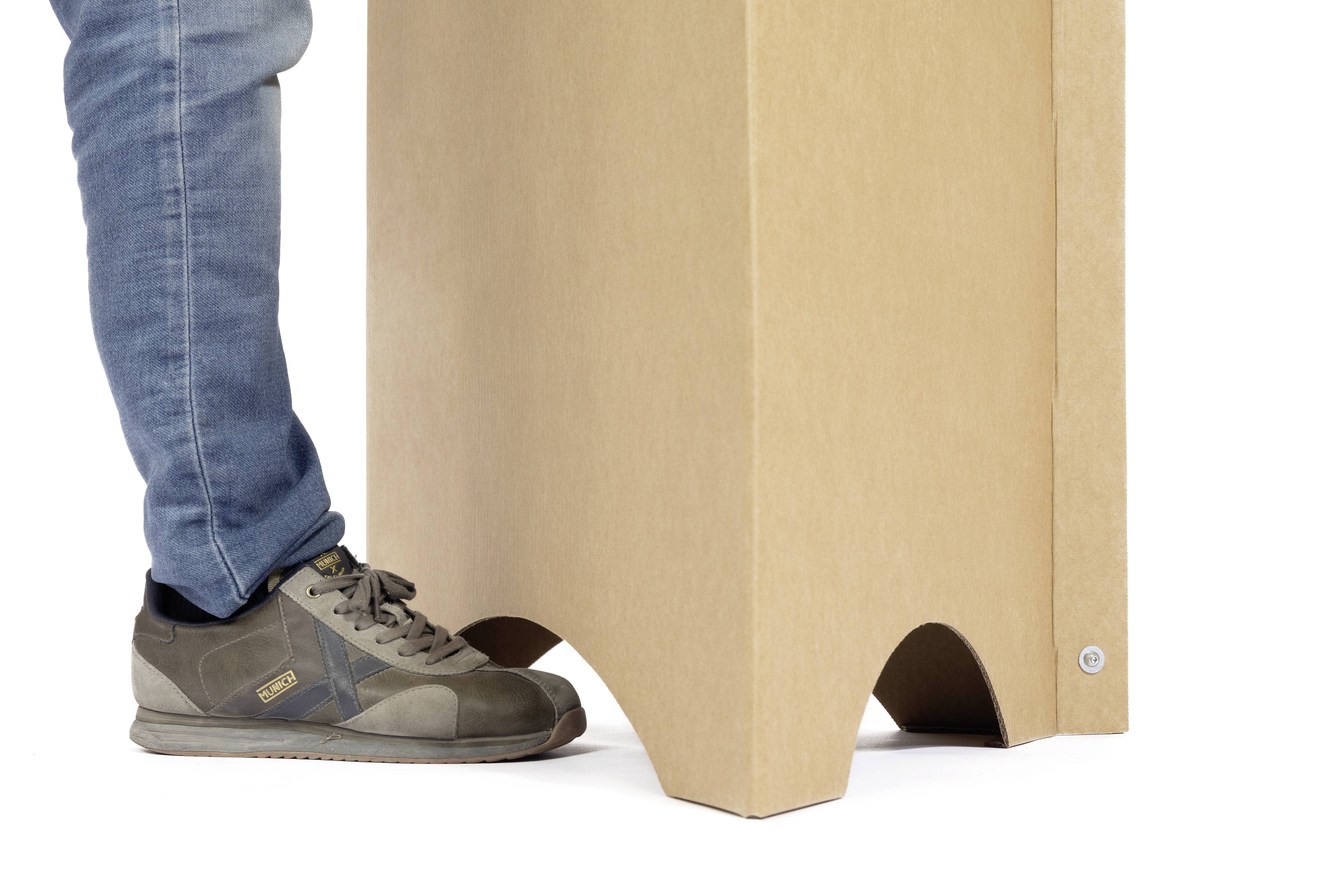 'Ein Bein in Jeans und Turnschuh drückt einen Kartonständer.'