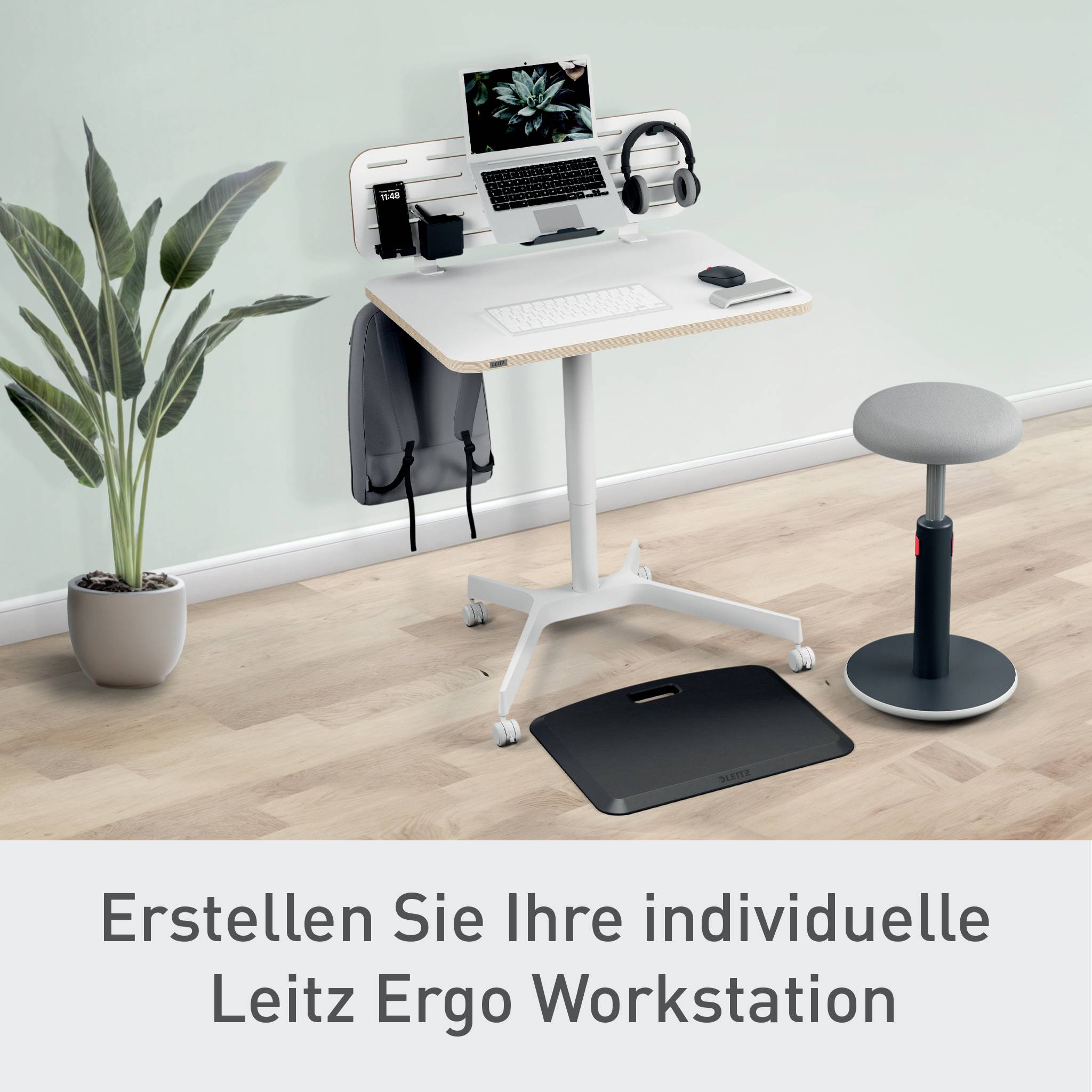 Ein heller Arbeitsplatz mit Schreibtisch, Bildschirm, Zubehör, Pflanze, ergonomischem Stuhl und Balance Board. Text: 'Erstellen Sie Ihre individuelle Leitz Ergo Workstation'.