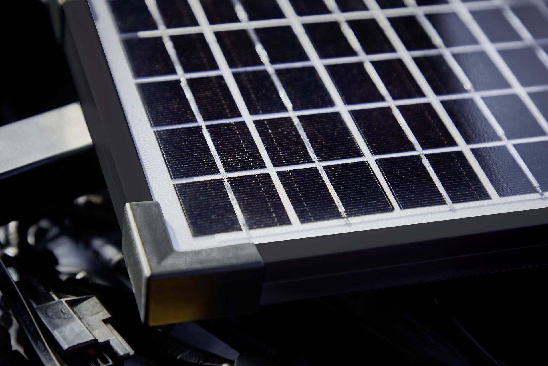 Nahaufnahme eines Solarmoduls mit dunklen Paneelen auf einer Metalloberfläche.