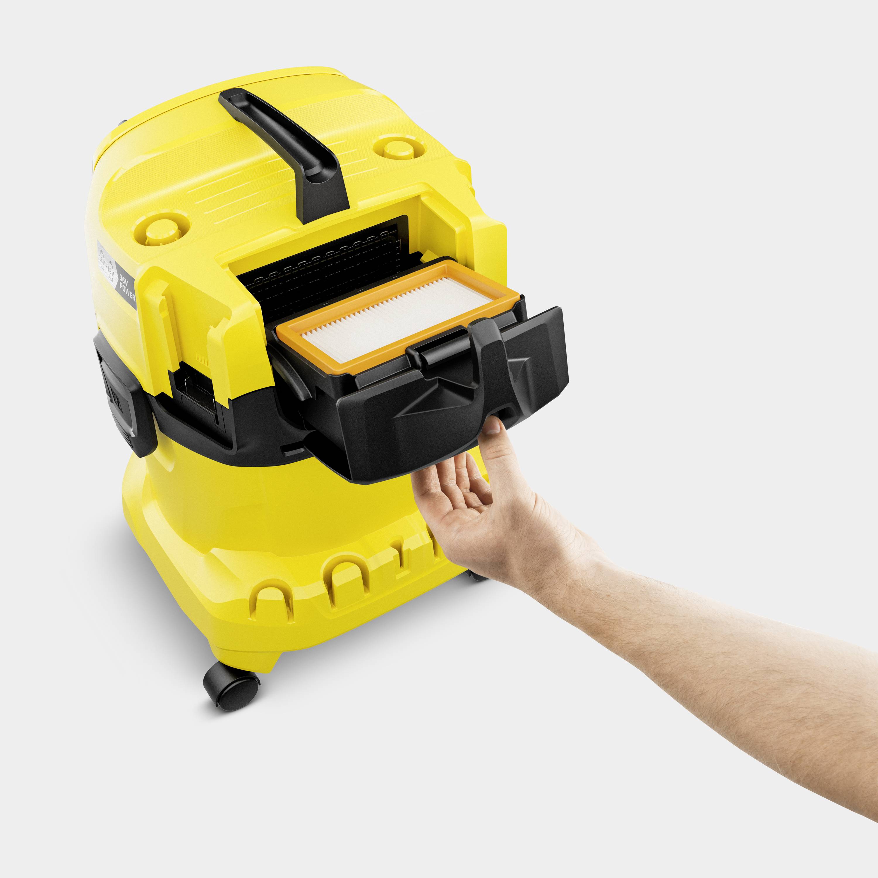 Ein gelber Staubsauger wird geöffnet, um den Filter zu tauschen. Eine Hand hält den neuen Filter bereit vor dem Staubsauger.