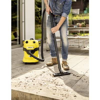 Eine Person benutzt einen gelben Industriesauger auf einer Holzterrasse, um Schmutz und Laub zu entfernen.