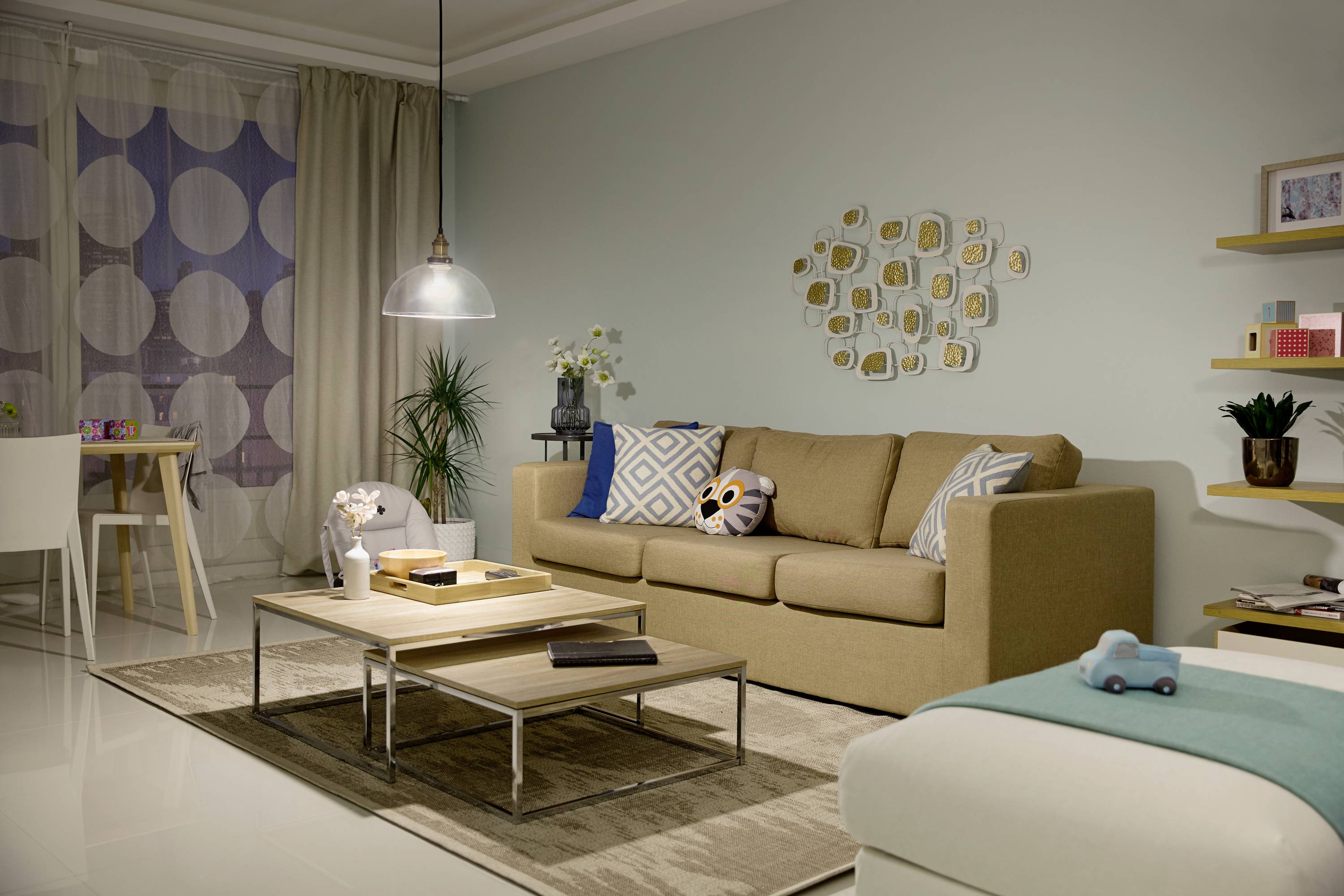 Gemütliches Wohnzimmer mit beigem Sofa, Couchtisch, minimalistischer Dekoration und weichen Farben. Essbereich im Hintergrund sichtbar.