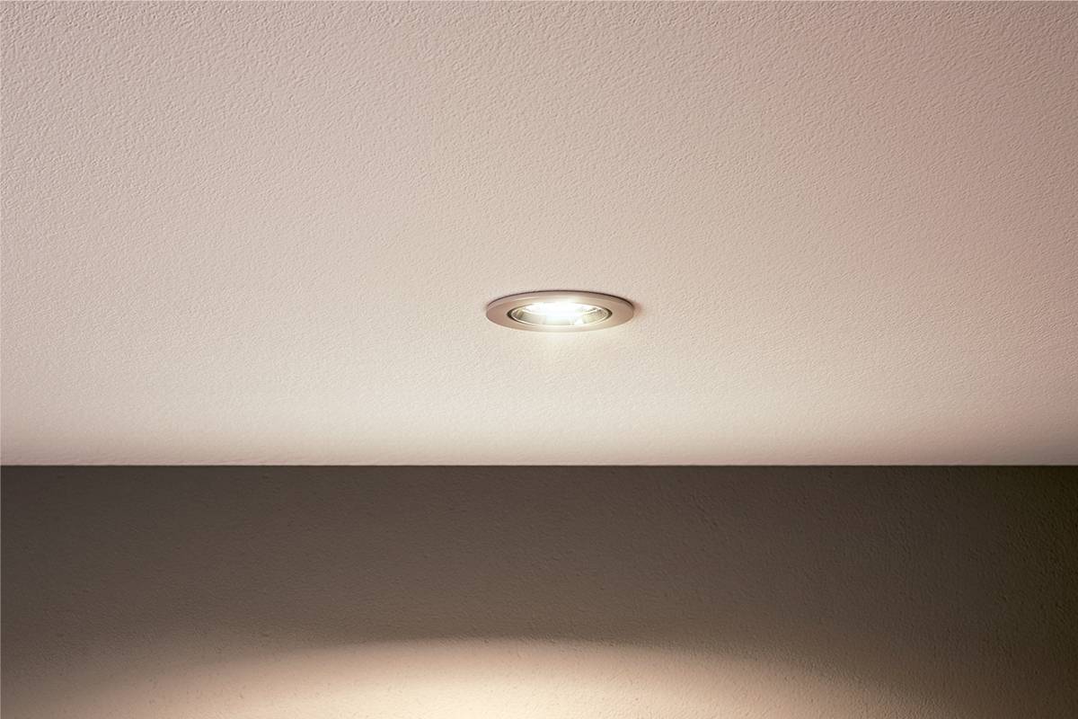 Eine in die Decke eingelassene Lampe strahlt sanftes Licht aus, beleuchtet die Umgebung gleichmäßig und schafft eine einladende Atmosphäre.