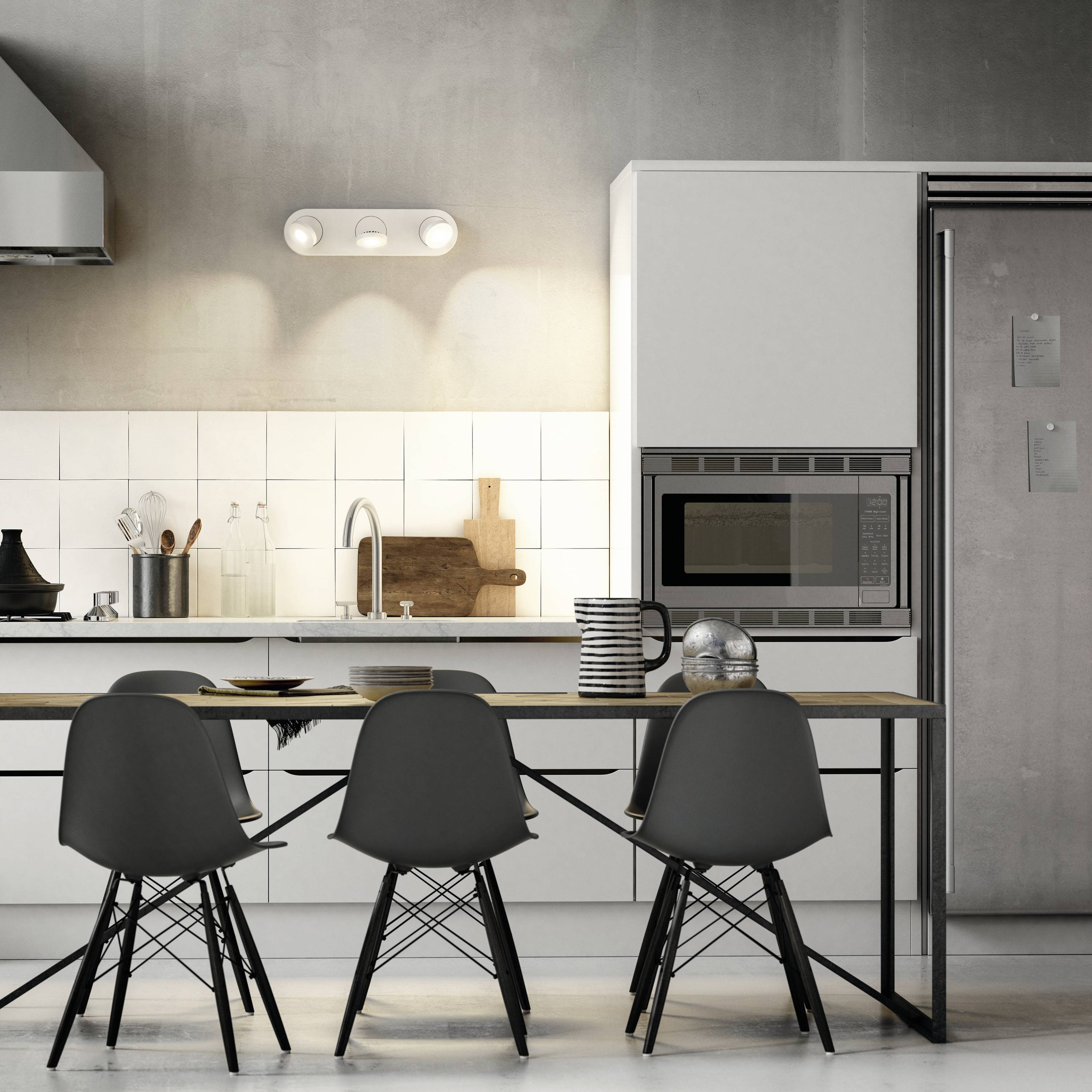 Moderne Küche mit Tisch, vier schwarzen Stühlen, einer Küchenzeile, Mikrowelle und heller Beleuchtung über Arbeitsfläche.