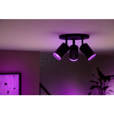 Eine moderne Deckenleuchte mit drei verstellbaren Spots strahlt violettes Licht aus, das einen Raum sanft beleuchtet.