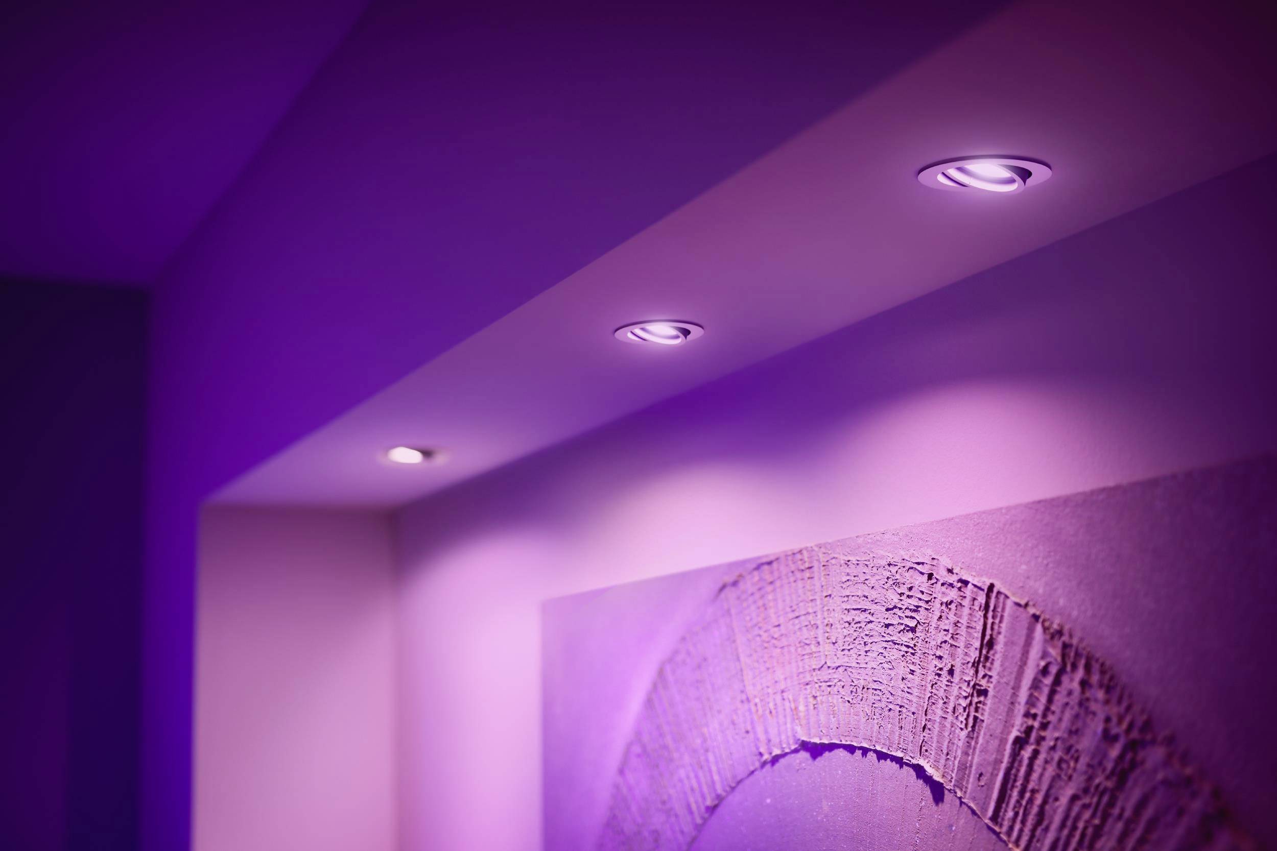 Lila Deckenbeleuchtung beleuchtet eine Wand mit einem abstrakten Kunstwerk. Die Szene wirkt modern und stimmungsvoll.