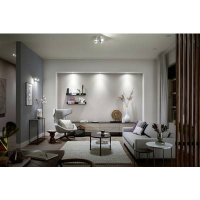 Moderner Wohnraum mit grauem Sofa, Beistelltisch, Sessel und dezenten Dekorationen. Kunstwerke an der Wand, neutrale Farben.
