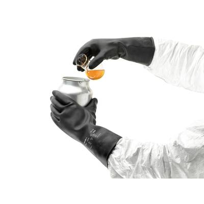 Eine Person in Schutzausrüstung gießt orange Flüssigkeit aus einem Becherglas in eine Metalldose. Hände tragen schwarze Handschuhe.