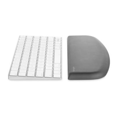 Weiße Computer-Tastatur neben einer grauen, gebogenen Handgelenkstütze auf einer weißen Oberfläche.