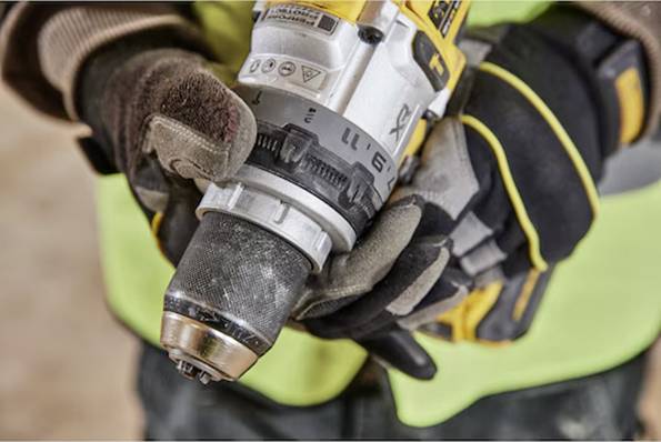 Eine Person mit Schutzhandschuhen hält eine Bohrmaschine und betont damit den Fokus auf Griffhaltung und Kontrolle während der Bauarbeit.