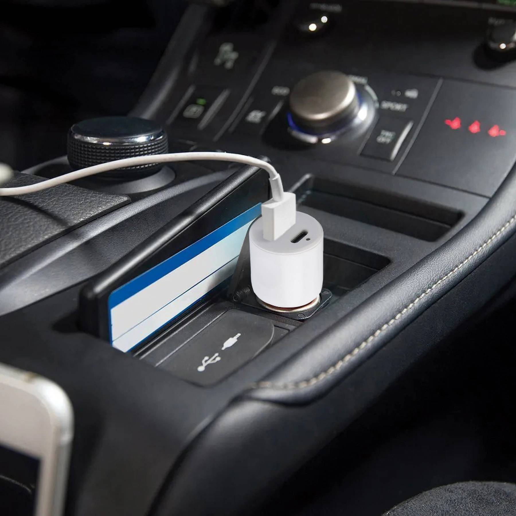 Ein Auto-USB-Ladegerät ist in den Zigarettenanzünder gesteckt, ein Kabel verbunden. Daneben liegen Karten im Fach der Mittelkonsole.